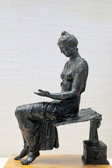 A bronze statue depicting a girl reading